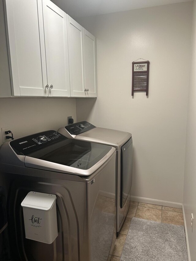 laundry room with baseboards, light tile patterned flooring, cabinet space, and washing machine and clothes dryer