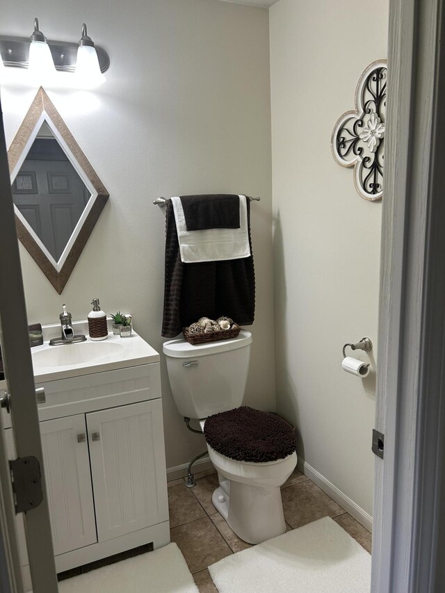 bathroom with baseboards, tile patterned flooring, vanity, and toilet