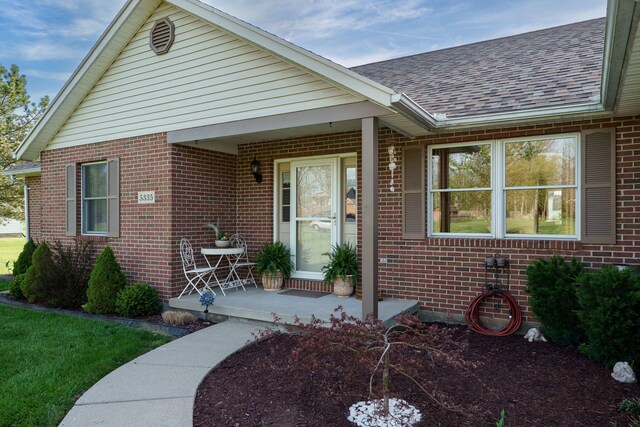 view of front of property with roof with shingles, a porch, and brick siding