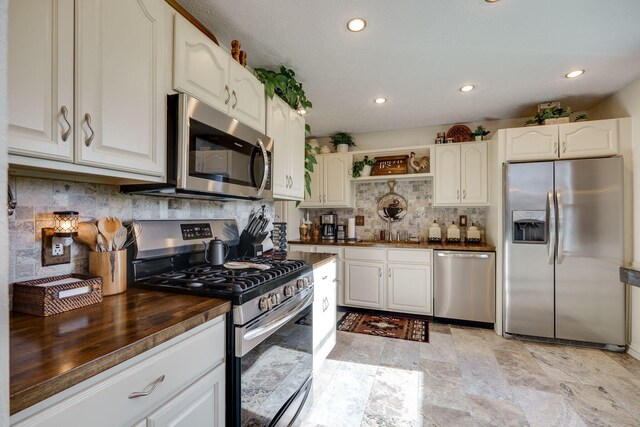 kitchen featuring butcher block counters, recessed lighting, white cabinetry, tasteful backsplash, and appliances with stainless steel finishes