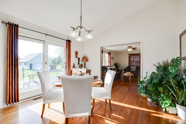 dining space featuring a notable chandelier, a wealth of natural light, lofted ceiling, and wood finished floors