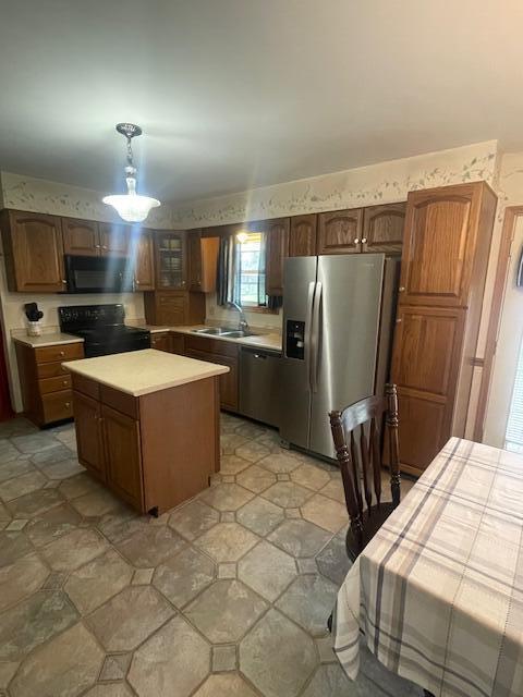 kitchen with light countertops, a center island, black appliances, and a sink