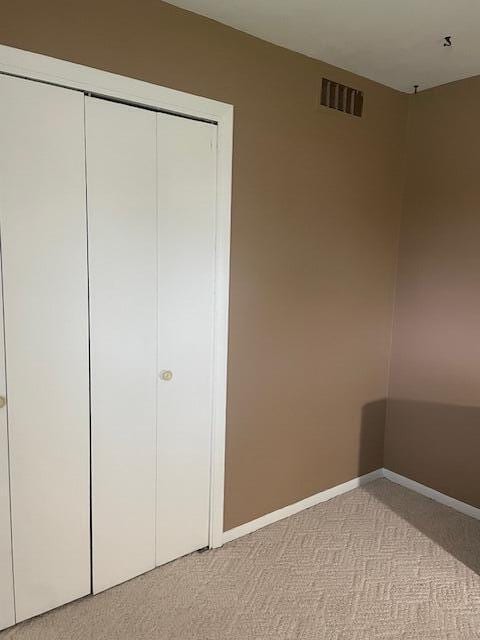 bedroom with light carpet, baseboards, a closet, and visible vents