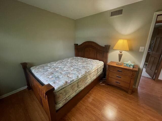 bedroom featuring baseboards, visible vents, and wood finished floors