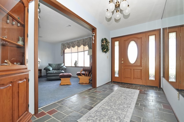 carpeted foyer with a chandelier