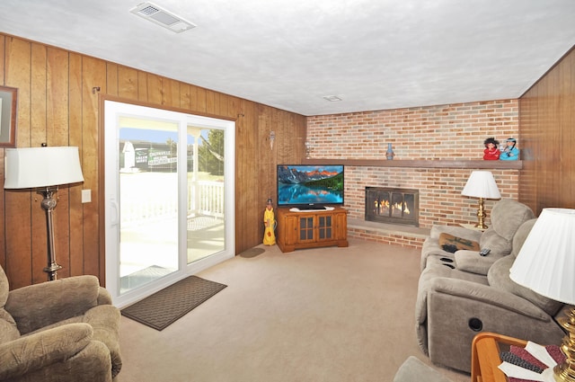 carpeted living room with a brick fireplace and wood walls