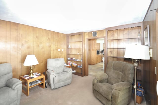 sitting room with light colored carpet and wood walls