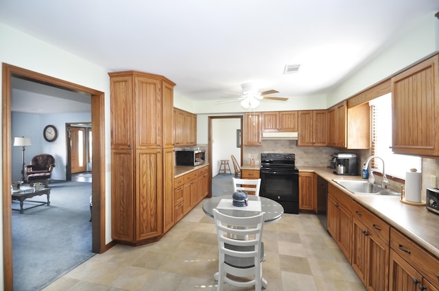 kitchen with sink, black appliances, light carpet, ceiling fan, and backsplash