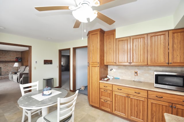 kitchen featuring tasteful backsplash, ceiling fan, and brick wall