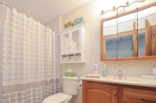 bathroom with vanity, toilet, curtained shower, and tile walls