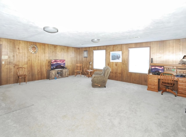 sitting room featuring wooden walls and light carpet