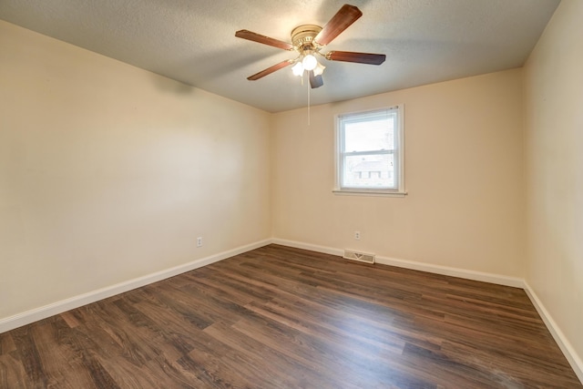 spare room with baseboards, dark wood-style floors, visible vents, and ceiling fan
