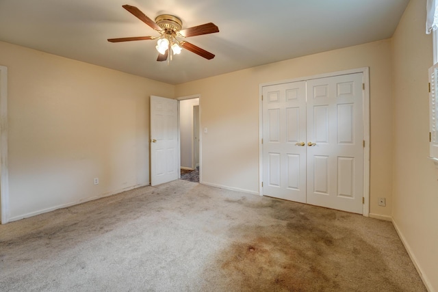 unfurnished bedroom featuring baseboards, ceiling fan, a closet, and carpet
