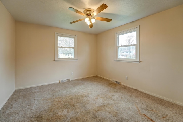 empty room with plenty of natural light, visible vents, and carpet