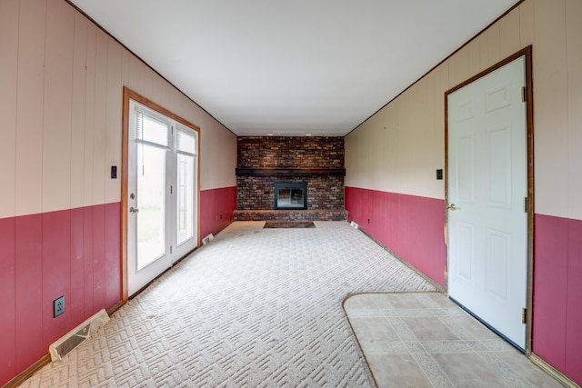 unfurnished living room with light carpet, a fireplace, and visible vents