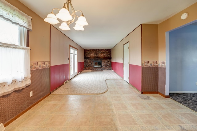 interior space with a wainscoted wall, visible vents, an inviting chandelier, and a brick fireplace