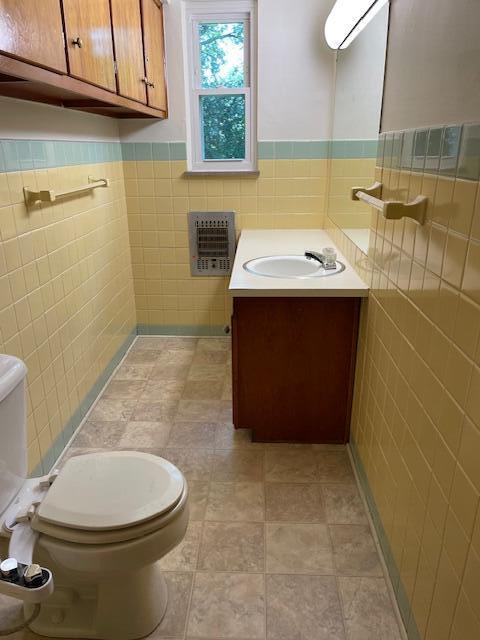 1401 E Home Rd, Springfield, OH 45503 - half bath featuring tile walls, heating unit, vanity, and a wainscoted wall