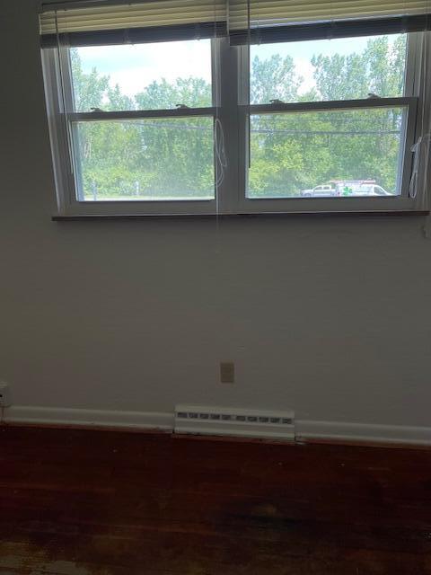 1401 E Home Rd, Springfield, OH 45503 - empty room with a baseboard heating unit, healthy amount of natural light, and wood finished floors