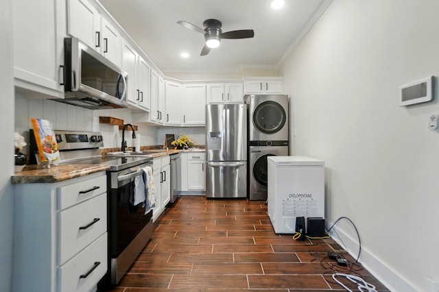 kitchen with crown molding, wood finish floors, appliances with stainless steel finishes, a sink, and stacked washing maching and dryer