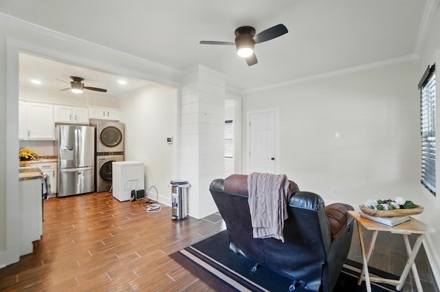 living room featuring stacked washing maching and dryer, ceiling fan, and ornamental molding