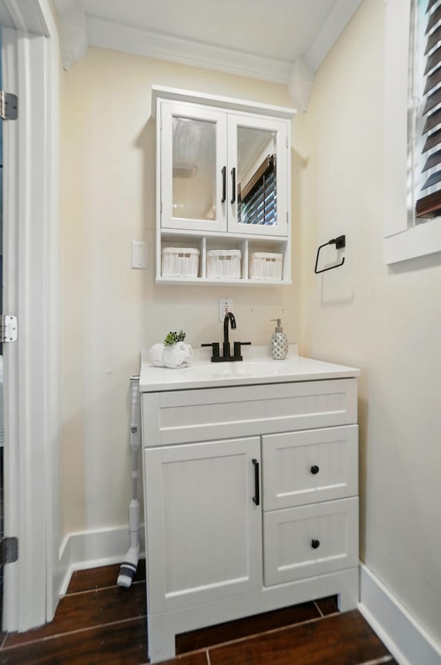 bathroom with baseboards, ornamental molding, wood finished floors, and vanity