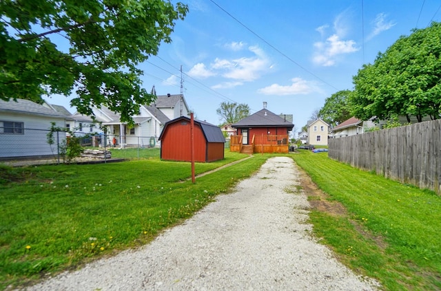 view of yard featuring fence, driveway, an outbuilding, and a shed