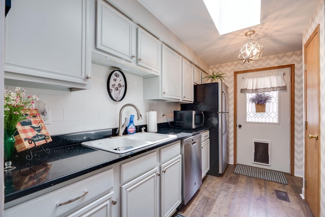 4212 Midfield St, Springfield, OH 45503 - kitchen with stainless steel appliances, wallpapered walls, dark countertops, light wood-style floors, and tasteful backsplash