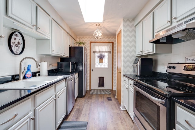 4212 Midfield St, Springfield, OH 45503 - kitchen with stainless steel appliances, wallpapered walls, under cabinet range hood, dark countertops, and a chandelier