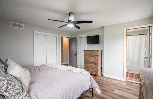 bedroom with ceiling fan, ensuite bath, multiple closets, and light wood-type flooring