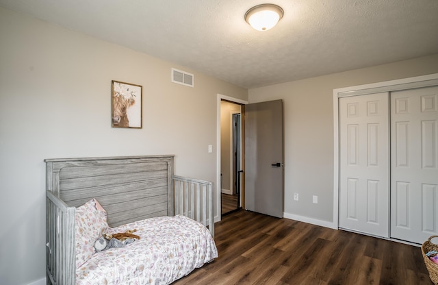 bedroom with dark hardwood / wood-style floors, a closet, and a textured ceiling