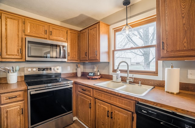 kitchen with stainless steel appliances, sink, and decorative light fixtures