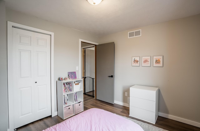 bedroom with dark hardwood / wood-style flooring and a closet