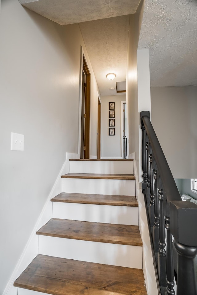 stairs featuring hardwood / wood-style flooring and a textured ceiling