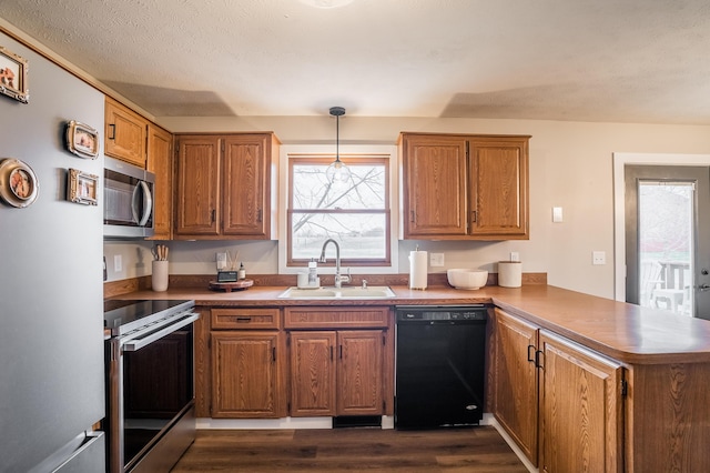 kitchen with sink, appliances with stainless steel finishes, dark hardwood / wood-style floors, kitchen peninsula, and pendant lighting