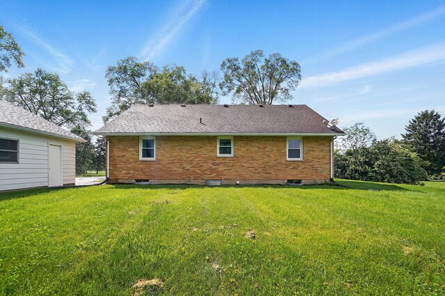 rear view of house featuring a lawn and brick siding