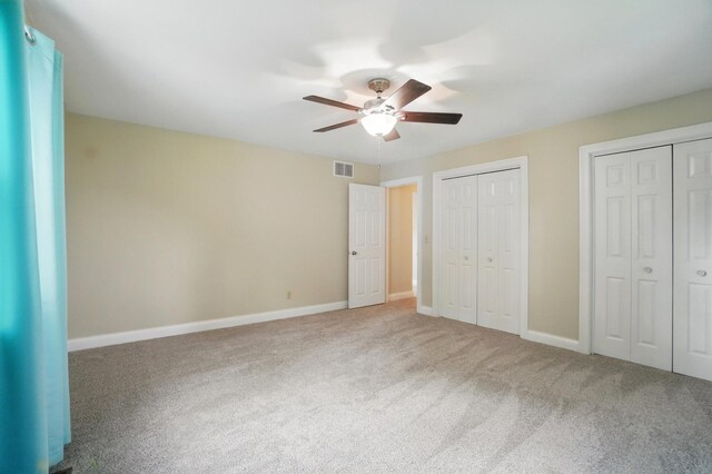 unfurnished bedroom with two closets, carpet, and baseboards