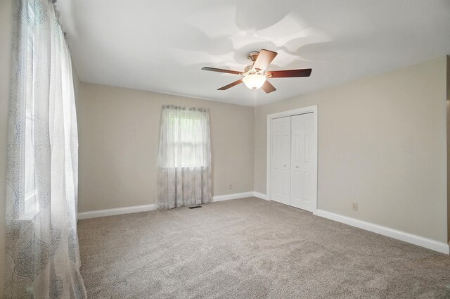 unfurnished bedroom featuring carpet flooring, a closet, baseboards, and ceiling fan