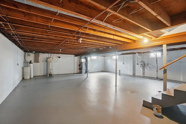 below grade area featuring electric water heater, a water softener, stairway, and electric panel