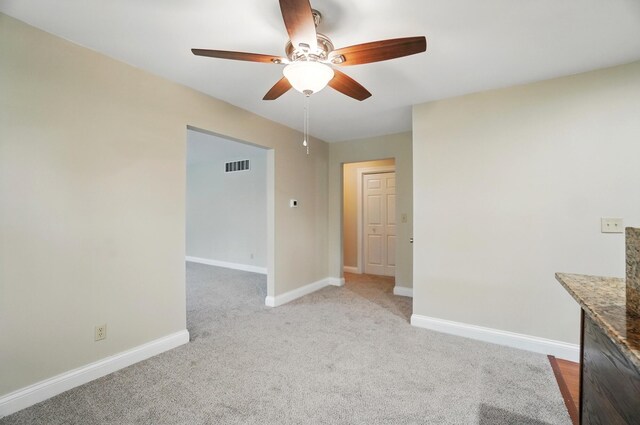 carpeted spare room featuring a ceiling fan and baseboards