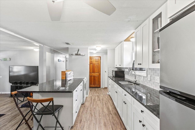 kitchen featuring white cabinetry, stainless steel refrigerator, a breakfast bar area, and white range with electric cooktop