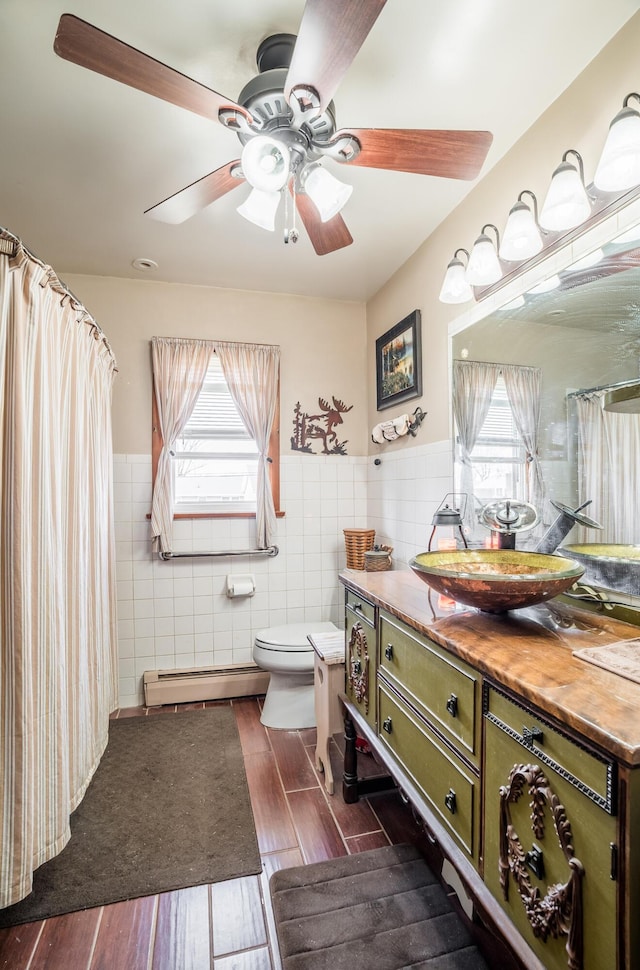 full bath with a healthy amount of sunlight, wood tiled floor, a baseboard heating unit, tile walls, and toilet