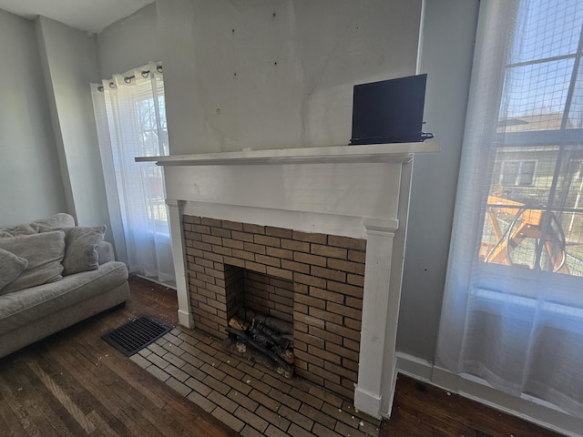 living room featuring a brick fireplace and dark wood-type flooring