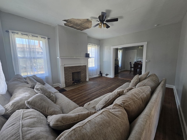 living room with dark wood-type flooring, ceiling fan, and a wealth of natural light