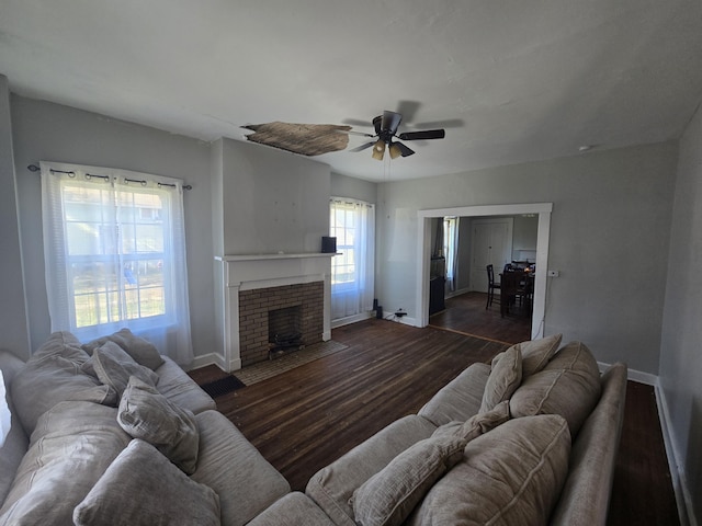 living room with ceiling fan, dark hardwood / wood-style flooring, and a brick fireplace