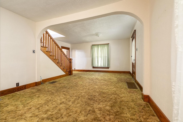 312 E Buckeye St, Belle Center, OH 43310 - carpeted spare room featuring arched walkways, stairs, a textured ceiling, and baseboards