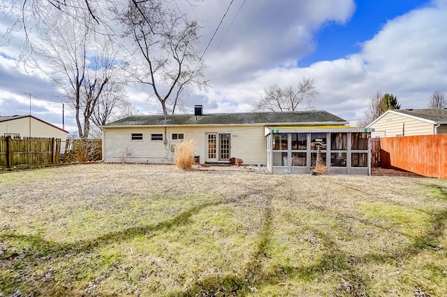 rear view of house featuring a fenced backyard and a sunroom