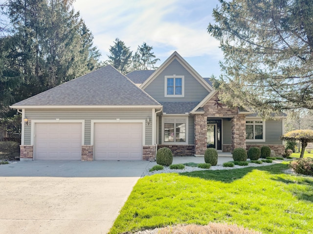 craftsman-style house with a front lawn, concrete driveway, an attached garage, stone siding, and roof with shingles