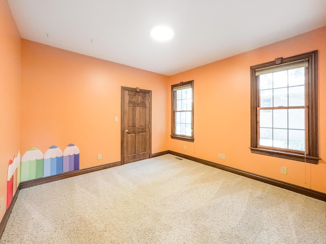 unfurnished room with carpet floors, visible vents, and baseboards