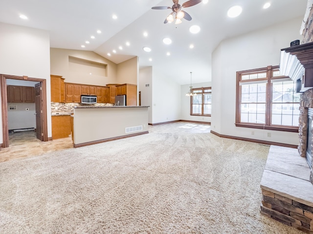 unfurnished living room with visible vents, light colored carpet, high vaulted ceiling, a ceiling fan, and a fireplace