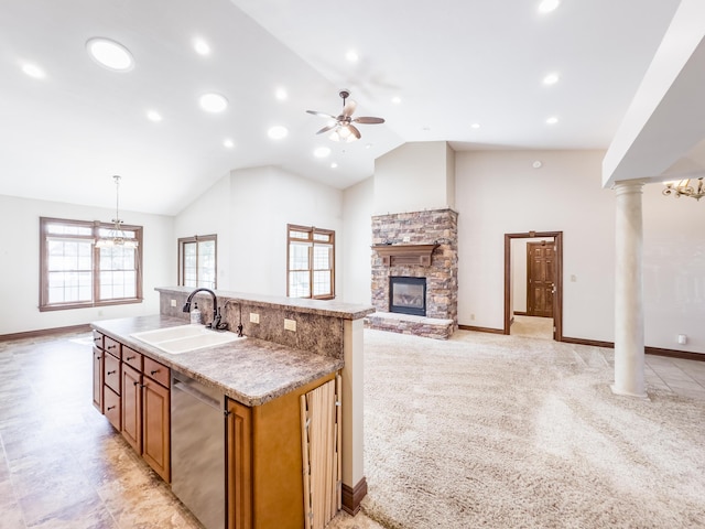 kitchen with a sink, a healthy amount of sunlight, ceiling fan with notable chandelier, dishwasher, and a stone fireplace